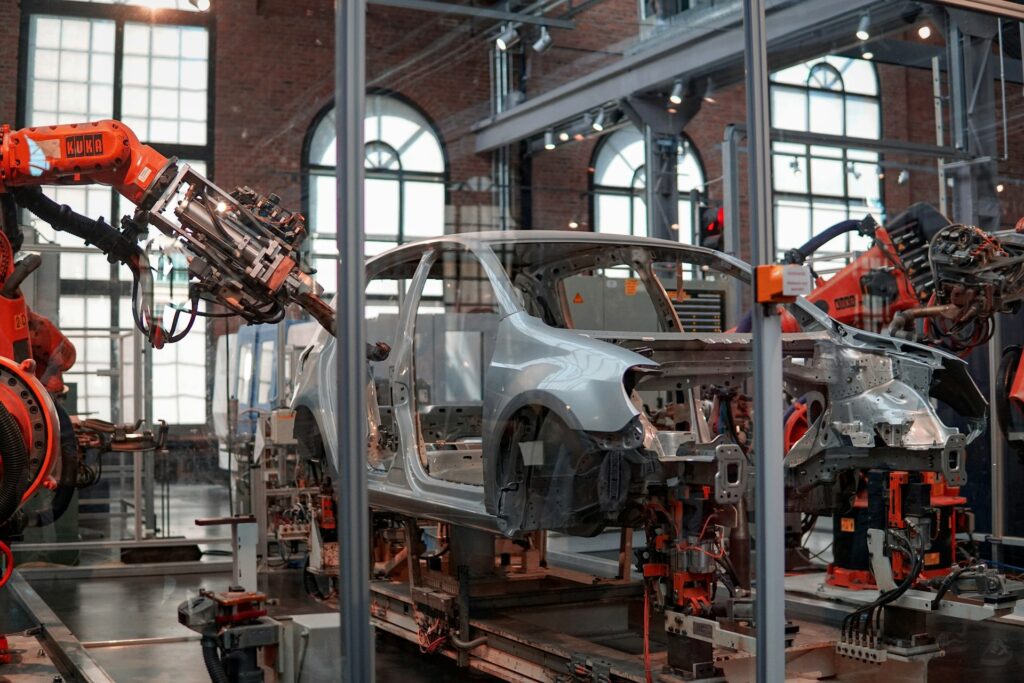 Bras robotiques industriels assemblant la carrosserie d'une voiture sur une ligne de production automatisée, illustrant les forts besoins électriques de l'industrie de pointe.