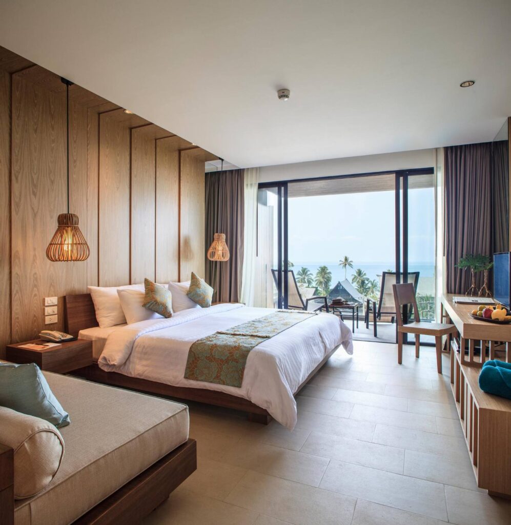 Chambre d'hôtel luxueuse avec vue sur mer et éclairage tamisé, illustrant la gestion optimisée du chauffage et de la clim par évole électricité.