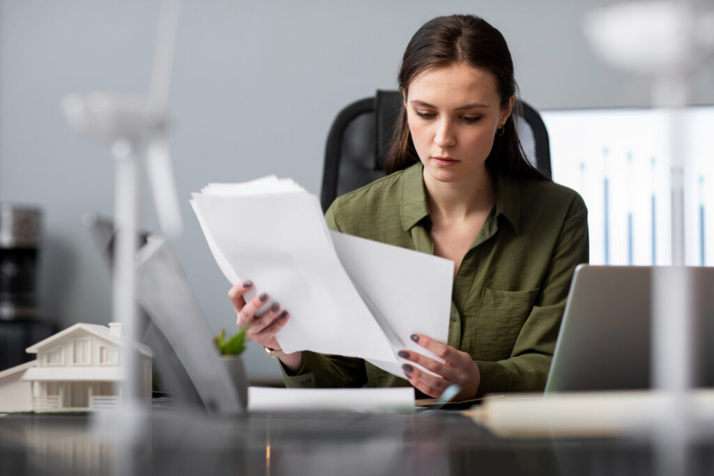 Une professionnelle examine des documents administratifs et des factures d'électricité à son bureau, illustrant les démarches de résiliation de contrat.